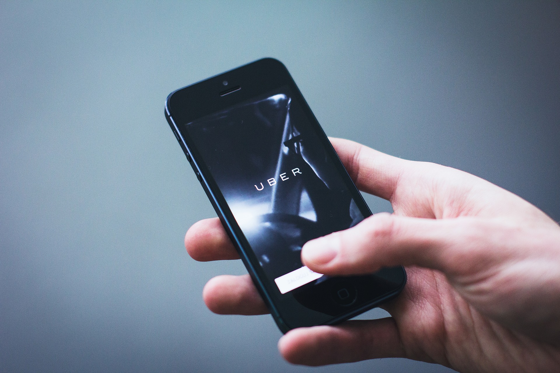 Closeup of a caucasian and holding and iPhone with the Uber App open, symbolizing the need for a liability lawyer in personal injury cases.
