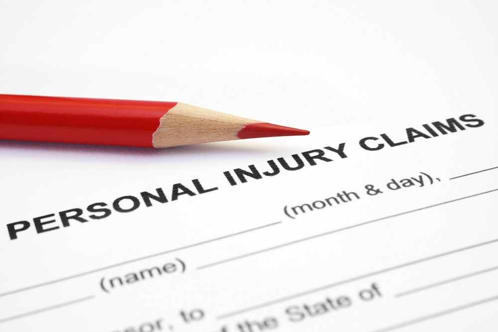 Closeup of a black and white personal injury case claim form, titled Personal Injury Claims, with a red colored pencil above the title, posing the question, What is personal injury on Philadelphia, PA?