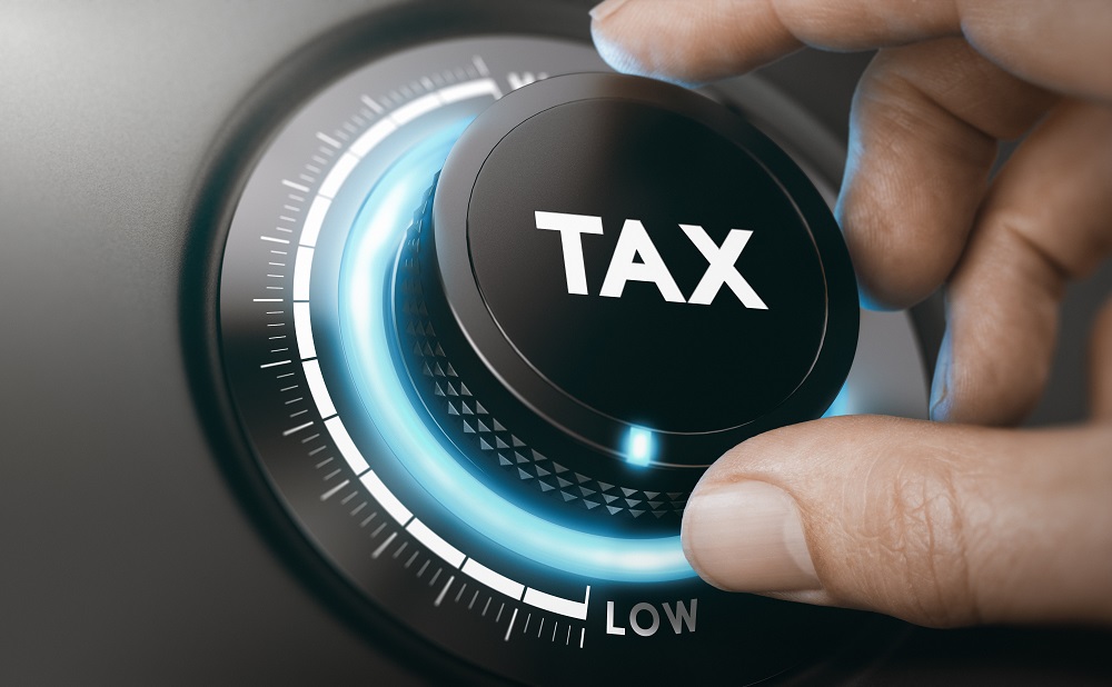 Two fingers are turning a backlit black knob with the word TAX on it from high to low, posing the question, Are Personal Injury Claims Taxable in Philadelphia?