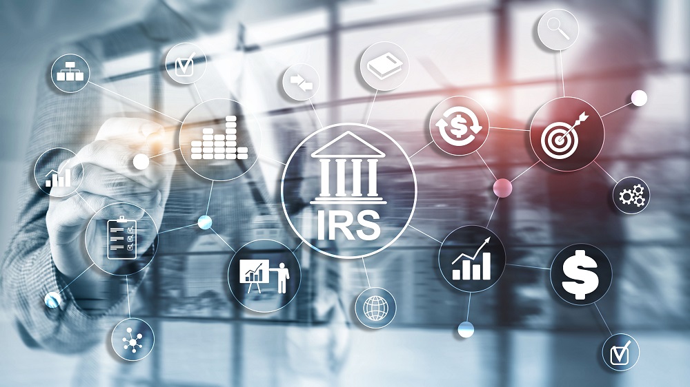 A graphic of transparent circles with images of graphs, dollar signs, etc. and one larger main circular graphic with a white icon of a Greek temple that says IRS in the middle. In the bluish grey background is a photo of a business man and woman, with the man seeming to touch the circles in the foreground, posing the question, Can the IRS take my personal injury settlement.