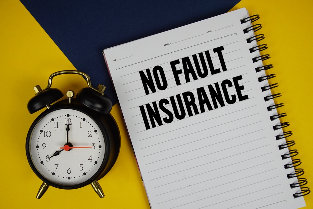 notebook showing no fault insurance text right next to an alarm clock