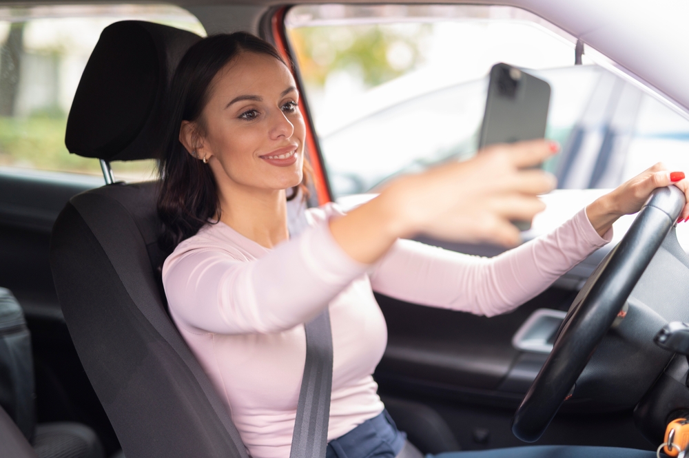 woman focusing on her phone while driving